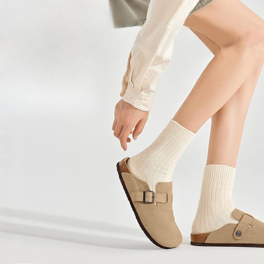 Woman wearing apricot Bali Clogs paired with cozy socks, showcasing a chic and comfortable casual outfit.